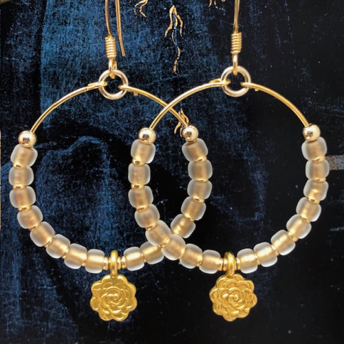 Boucles d'oreilles créoles composées de perles de rocaille japonaises dorées et d'une breloque en forme de fleur. Bijoux bohème chic.