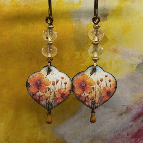 Boucles d'oreilles asymétriques bohèmes composées de pendentifs en cuivre émaillé en forme de coeur, avec un motif de fleurs orange. Bijoux uniques.