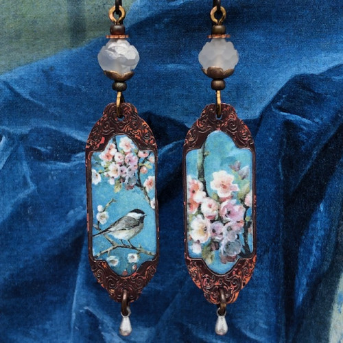 Boucles d'oreilles bohèmes asymétriques composées de pendentifs en cuivre émaillé représentant un oiseau et une branche de cerisiers. Bijoux uniques.