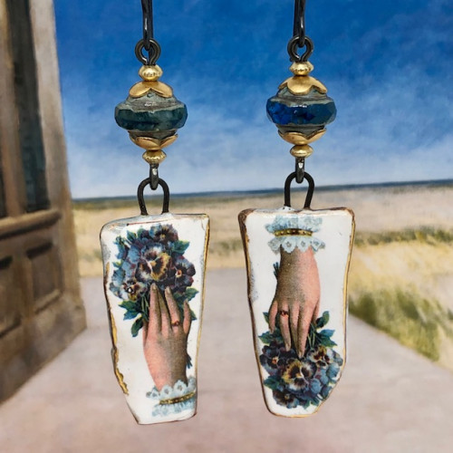 Boucles d'oreilles bohème composées de pendentifs en céramique représentant une main tenant un bouquet de pensées. Pièces uniques.