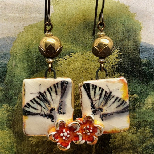 Boucles d'oreilles bohèmes composées de pendentifs artisanaux représentant un papillon noir et une fleur orange. Bijoux uniques.