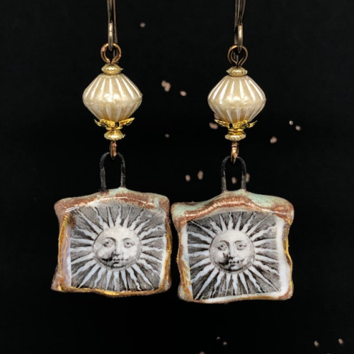 Boucles d'oreilles bohème composées de pendentifs artisanaux en céramique représentant un soleil au visage énigmatique. Pièces uniques.