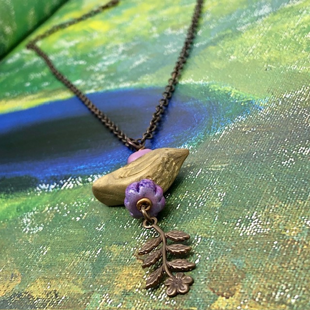 Collier ras-de-cou bohème composé d’un pendentif artisanal kaki en forme d'oiseau et de perles violettes; Chaîne en laiton. Bijou unique.